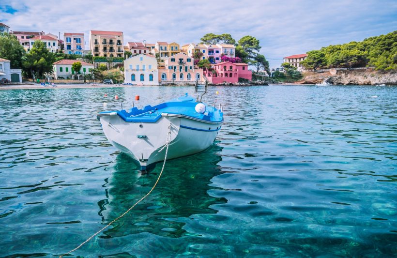 White fishing boat in the blue rippled sea water bay in Assos village, Kefalonia island, Greece.